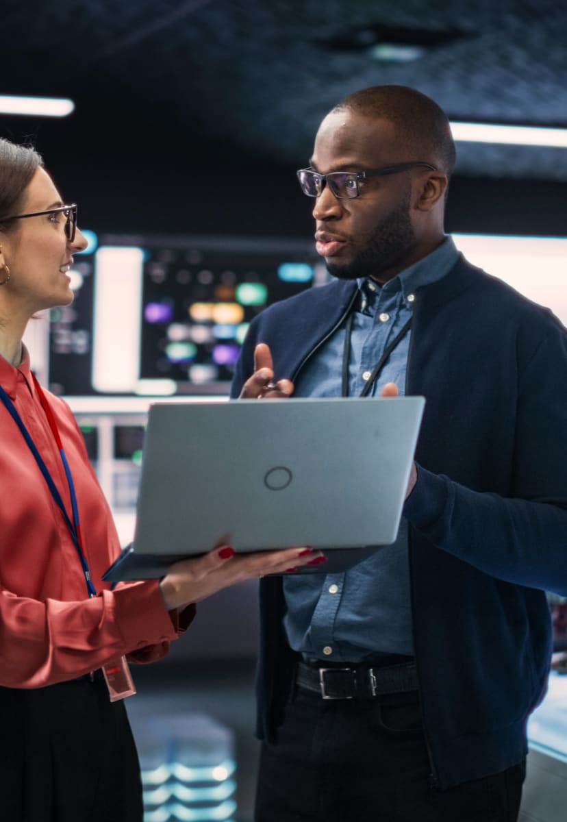 man and woman standing and working on a laptop in an office